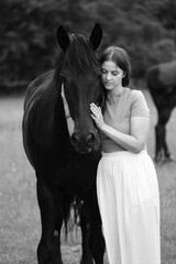 A young woman and her icelandic horse working and cuddle together. Woman lovingly pets a horse in a...