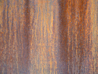 Rusty metal surface showing signs of corrosion and weathering, creating an abstract pattern of orange and brown hues, suitable for backgrounds and textures