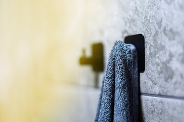 Gray terry bath towel hanging on a hook, ready for use on a bright sunny day, clean and fresh...