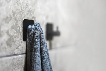 Gray terry bath towel hanging on a hook, ready for use in a bathroom or spa setting