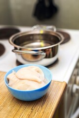 aw cleaned squid meat in a blue ceramic bowl with a metal cooking pot in the background, seafood preparation concept