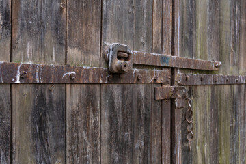 A perspective view of an old wooden barn gate. There is a rusty metal latch. Background. Texture....