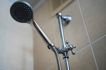 Metal thumbwheel adjuster for changing showerhead height, showcasing practical bathroom hardware in...