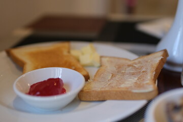 Female hand put Jam on Bread toast, glass of orange juice, sprigs spring tree with flowers, White Stone Background. Breakfast concept. Toast butter jam
