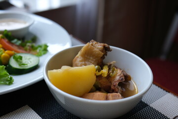 Spicy bbq chicken legs with grilled oranges, onions, garlic and potatoes close-up on a plate on a table. horizontal top view from above . High quality photo