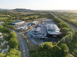 Aerial Drone View of Modern Car Dealership with Solar Panels and Large Parking Lot in Countryside...