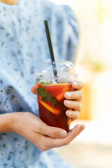 A cheerful person enjoys a colorful drink with mint and citrus while relaxing in a sunny outdoor setting