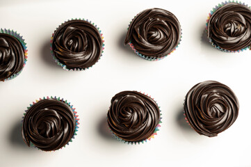 Top view of delicious chocolate cupcakes arranged neatly on clean white background — sweet dessert flat lay for food styling and bakery presentation

