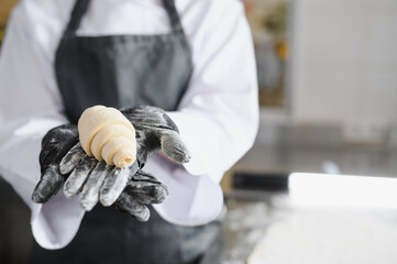 Baker showing freshly made raw croissant dough in bakery