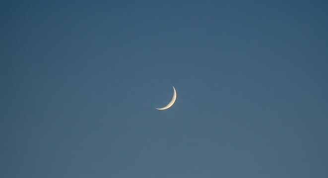 Thin crescent moon in a deep blue sky