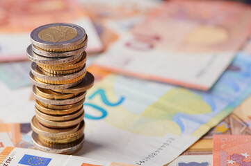 Stack of coins on top of colorful euro banknotes in a financial setting