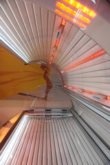 Inside solarium tanning bed with UV lamps and red light beauty salon background