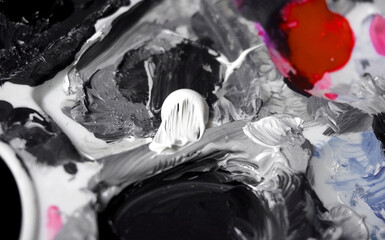 Abstract monochrome acrylic paint palette with black and white smears and red accent close up