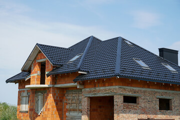 New residential building under construction with brick exterior and roofing details during bright daylight