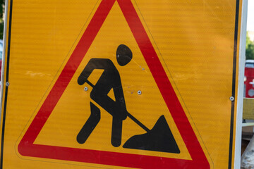 Construction work ahead warning sign indicating ongoing road repairs in a city setting during...