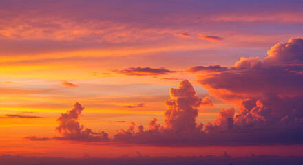 Fototapeta premium Vibrant sunset paints the sky with fiery oranges, deep purples, and soft pinks, illuminating dramatic, textured clouds in a breathtaking atmospheric display.