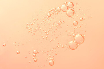 Minimal macro shot of golden-orange oil bubbles in water, scattered across a soft peach gradient background, creating a warm and airy composition. macro photography