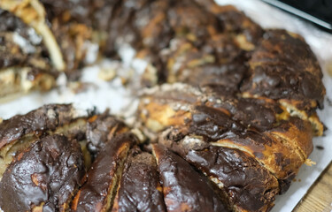 A rustic and appetizing close-up of a freshly baked chocolate babka, or a similar braided cake, with rich dark chocolate filling visible in the layers.