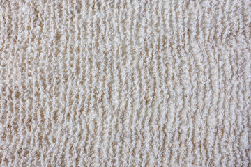 Close up of knitted beige fabric texture. Soft natural yarn textile background for craft, sewing, and design use.