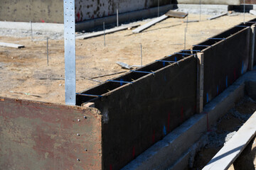 New house in beginning stage on job site, foundation dug out and wood cement forms in place, residential neighborhood housing development
