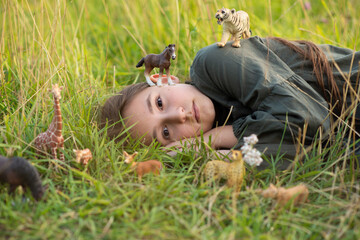 girl in the grass among toy animals. concept explore the world.