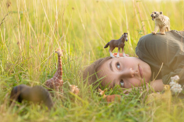 girl in the grass among toy animals. concept explore the world.