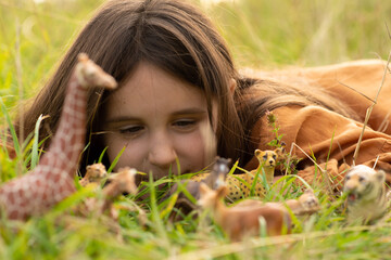girl in the grass with toy animals. child studying the surrounding nature. game for studying animals