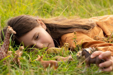 girl in the grass with toy animals. child studying the surrounding nature. game for studying animals