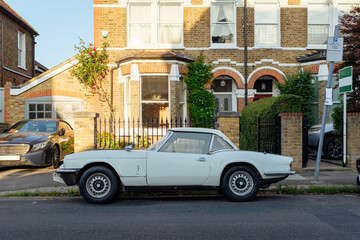 White vintage car parked in front of london house