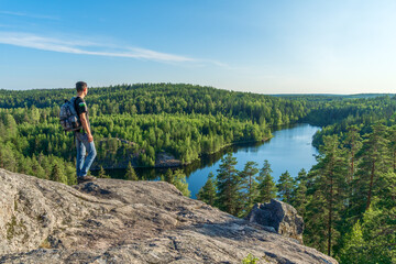 Man tourist standing on a rock, mountain and looking at the lake. Concept of sport, travel,...