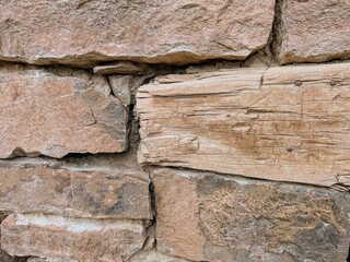 Rustic stone wall texture with worn-out natural wooden beam