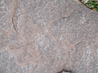 Rough stone surface in natural environment with grassy details visible