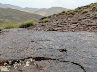 Close-up of rugged rock with mountainous landscape in the background