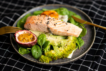 Grilled salmon fillet and fresh vegetable salad. Healthy keto food - green salad and grilled salmon on black background, space for text.