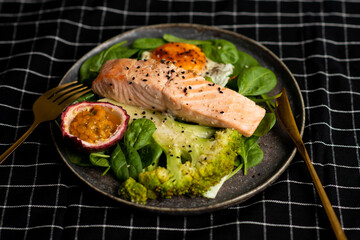 Grilled salmon fillet and fresh vegetable salad. Healthy keto food - green salad and grilled salmon on black background, space for text.