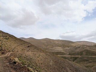 Arid mountainous terrain under cloudy skies in the Atlas Mountains region