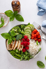 Healthy lunch bowl with grilled chicken, rice, fresh vegetables and arugula