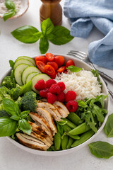 Healthy lunch bowl with grilled chicken, rice, fresh vegetables and arugula