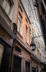 Low angle view of narrow historic alleyways and tall aged buildings in the Caruggi district of Genoa