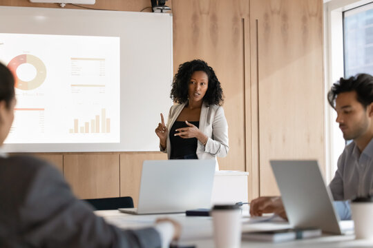Project pitch. Focused young woman entrepreneur manager ceo giving startup presentation at modern boardroom with digital screen convince corporate businesspeople audience in new idea strategy benefits - Powered by Adobe