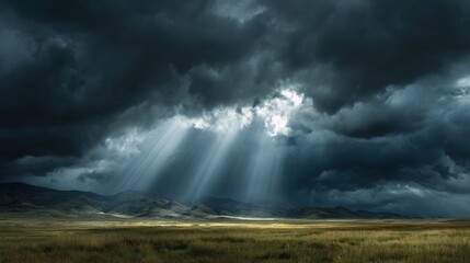 Dramatic sunbeams pierce dark storm clouds over a vast, grassy plain before distant mountains