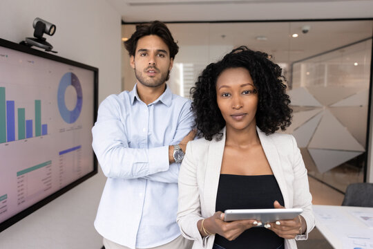 About us. Workplace portrait confident business professionals multicultural team of young man woman executives team leaders startup creators stand in modern office with digital tools looking at camera