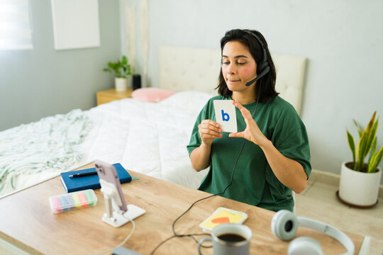 Latin teacher making a video call with students showing a flash card with letter b