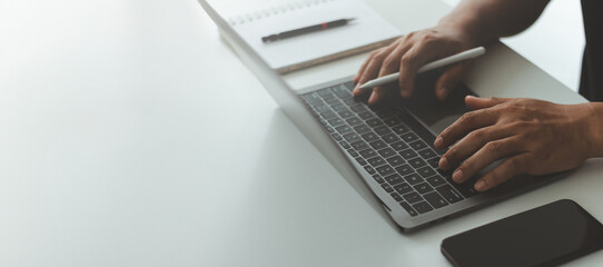 Hands typing on a laptop keyboard, with a smartphone on the desk, remote work, freelance lifestyle,...