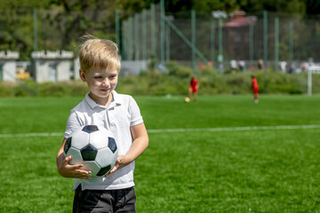 Little boy with soccer ball on football field during training