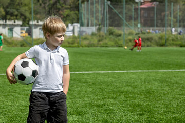 Boy holding soccer ball on football field during training