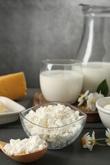 Fresh dairy products and flowers on grey wooden table against textured background, closeup