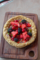 Imagen vertical de una pizza pequeña de frutas sobre una tabla de madera