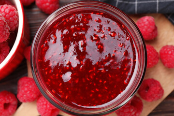 Sweet raspberry jam in glass jar and berries on table, flat lay