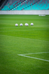 Soccer balls soft blurred waiting on lush green field in empty stadium. Focus on the grass and white line.